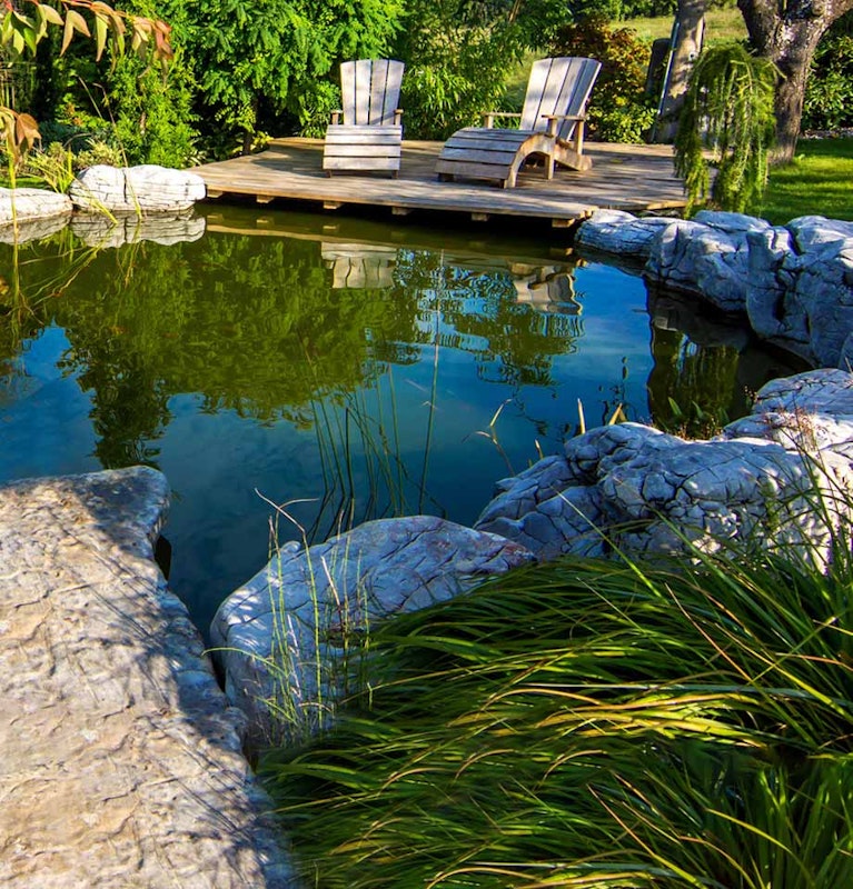Ein idyllischer Garten mit Teich und gemütlicher Sitzgelegenheit auf einem Holzdeck