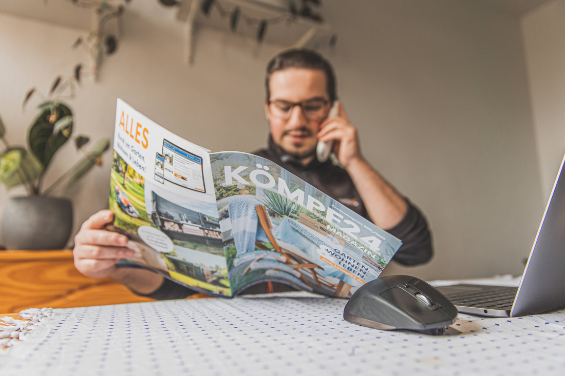 Mann ließt KÖMPF24-Magazin und telefoniert mit dem Kundenservice