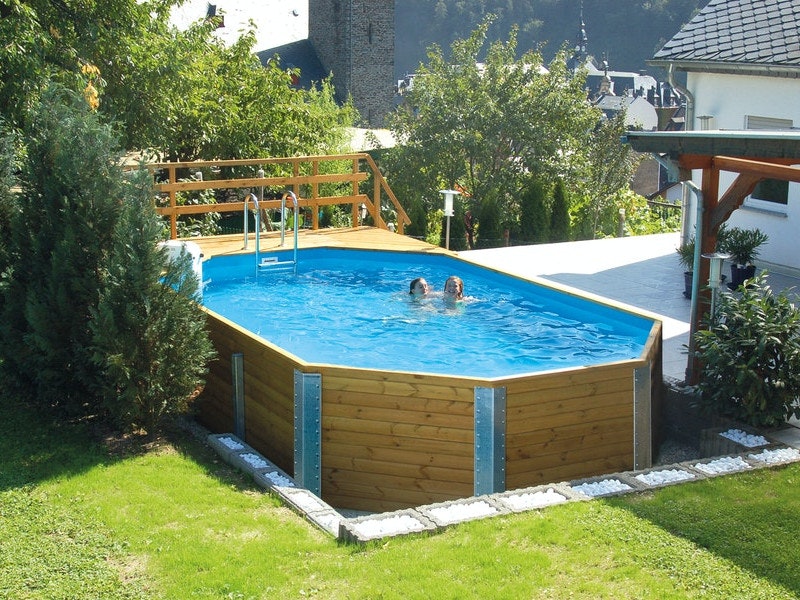 Ein Garten mit einem großen Pool aus Holz in dem zwei Mädchen schwimmen