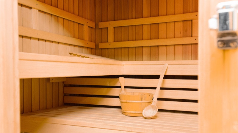 Blick in eine Sauna mit Wasserbottich und Schöpfkelle