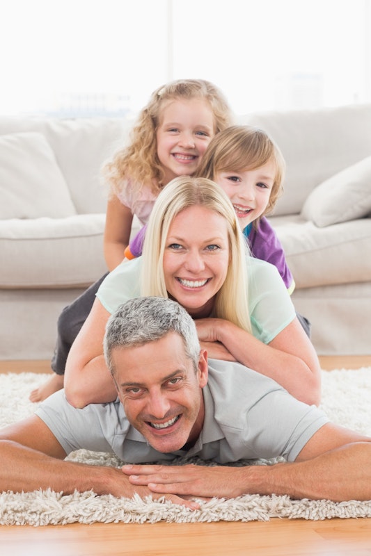 Vater mit grauen Haaren, blonde Mutter und zwei Kinder auf dem Boden