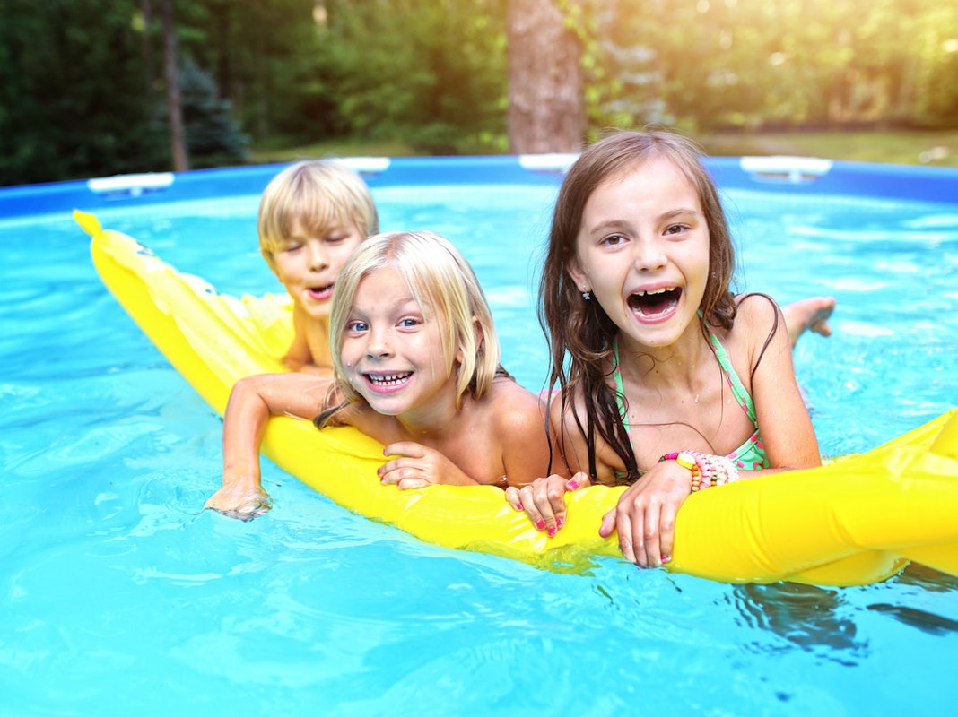 3 Kinder auf einer Luftmatratze im Pool