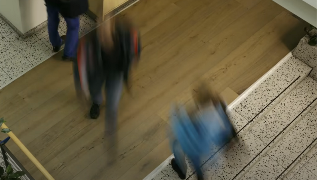 Menschen laufen über einen Holzboden in einem Treppenhaus